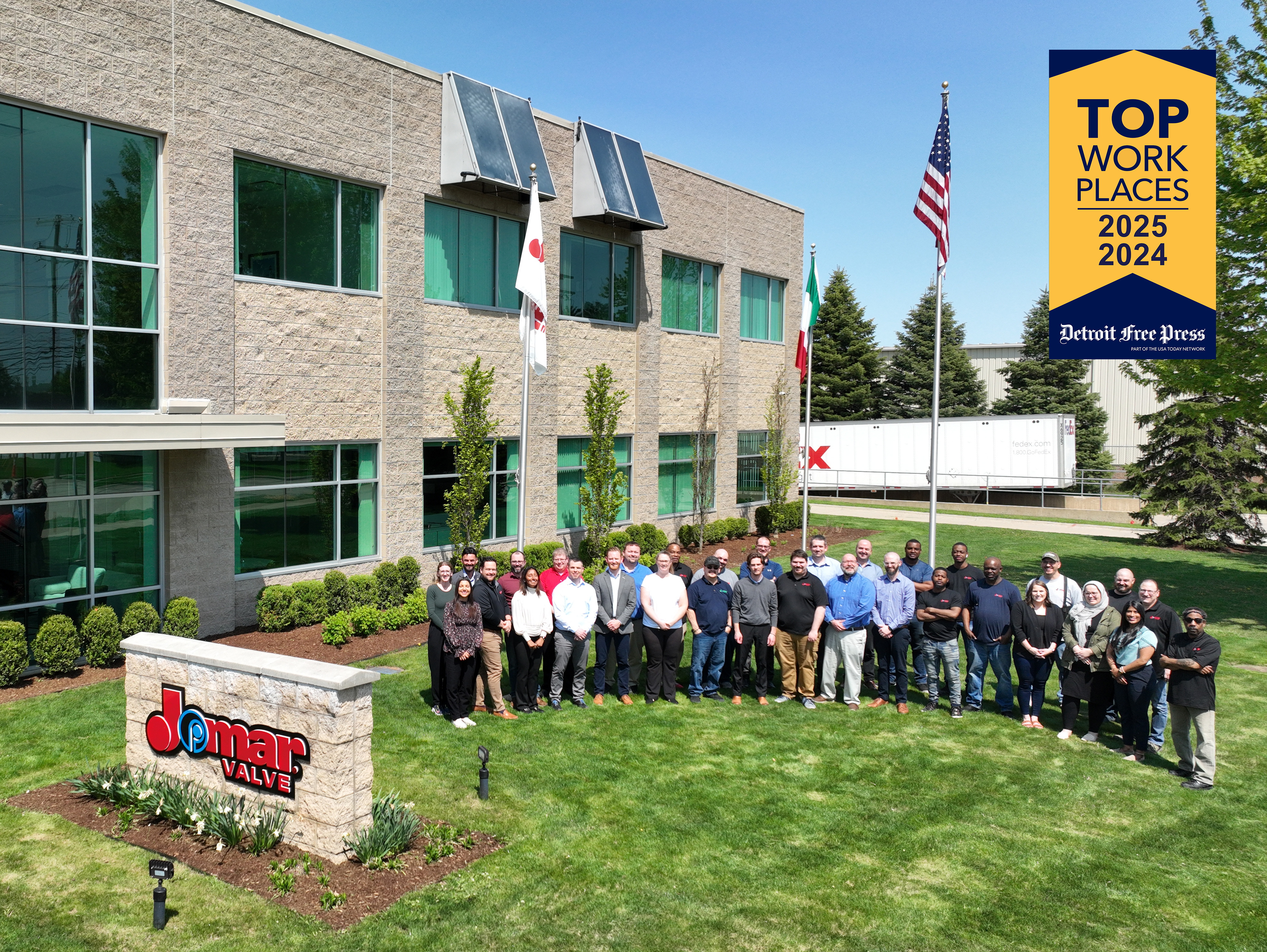 Jomar Valve Team Picture Jomar Valve Team Picture - A group of diverse people stands smiling in front of a modern office building with "Jomar Valve" signage. An award banner reads "Top Work Places 2024-2025."